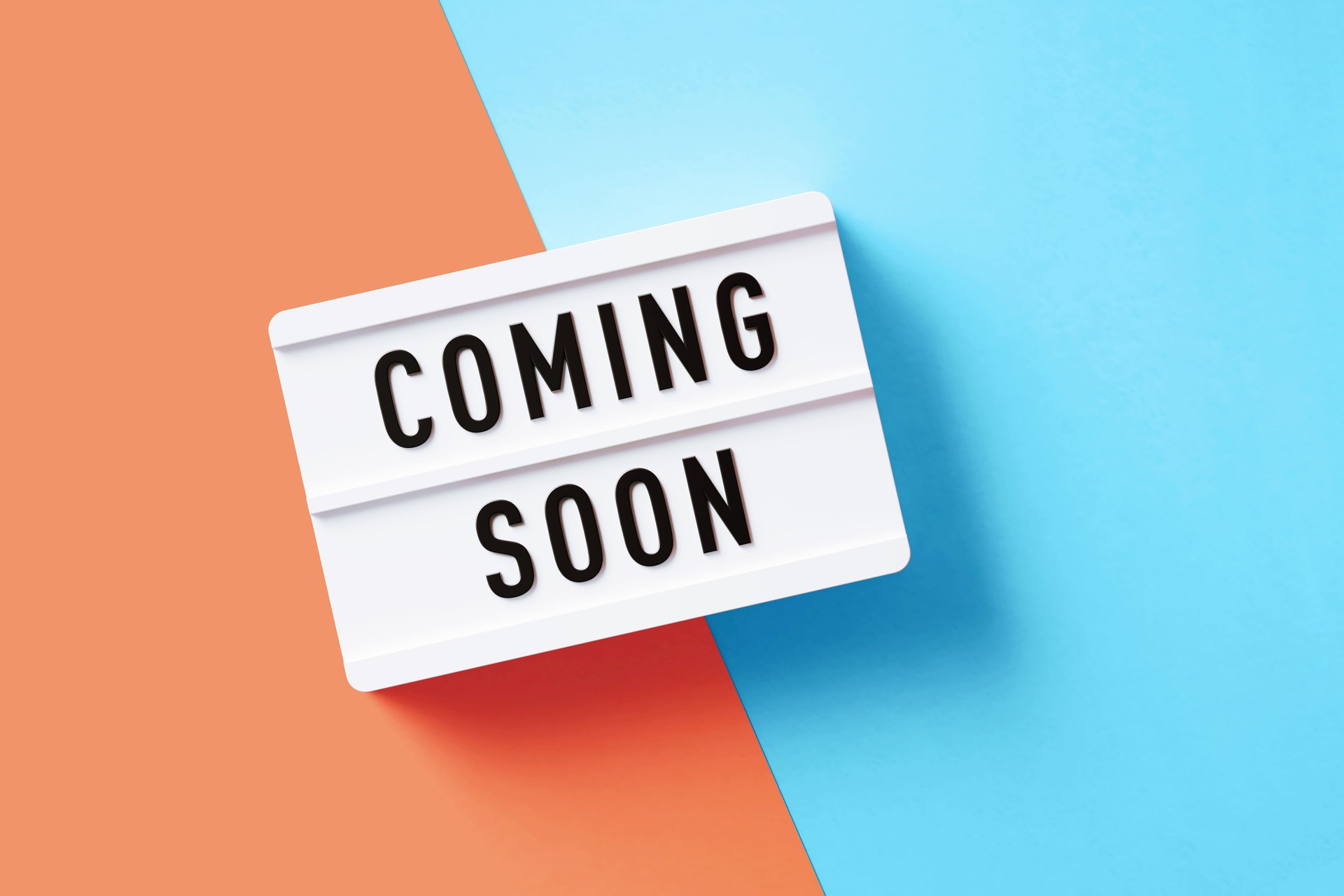Coming Soon Written White Lightbox Sitting On Pink And Blue Background